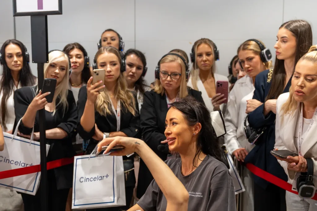 Klaudia Petela prowadzi pokaz zabiegu na modelce podczas wydarzenia The Art of K-Esthetic; uczestniczki obserwują pracę na stanowisku